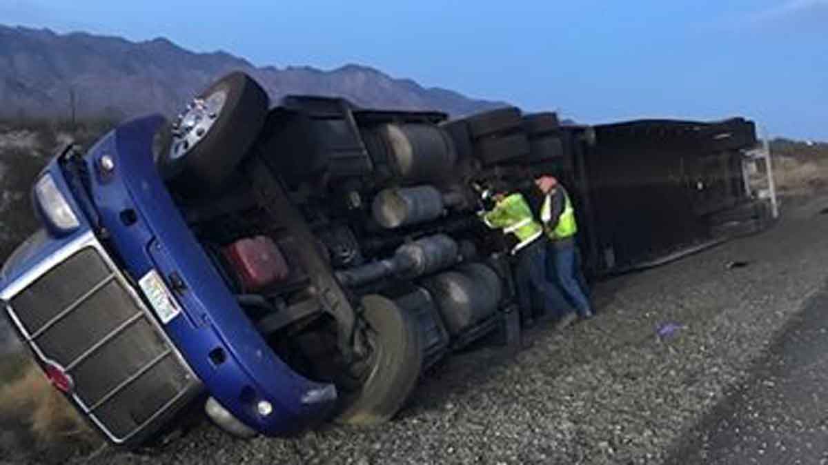 Workers recovering semi truck roller on freeway